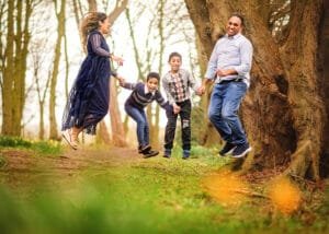 Family jumping and laughing together during a springtime outdoor family photography session