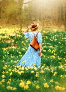 Outdoor Female Portrait Photography – A woman in a flowing blue dress walks through a golden daffodil field in Nottingham, embracing freedom and confidence.