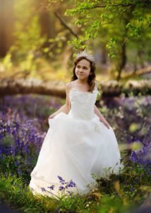 Girl in white dress standing in bluebell forest for First Holy Communion Photography