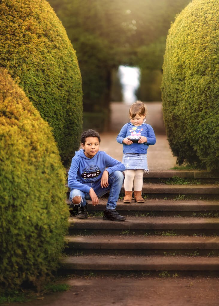 Portrait of siblings sitting on stairs at Elvaston Castle Park during a family outdoor photoshoot in spring. Captured by Nottingham Family Photographer.