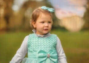 Portrait of a joyful toddler girl amidst blooming daffodils in spring, captured during a family photoshoot at Elvaston Castle Park in Derby by Nottingham Family Photographer.