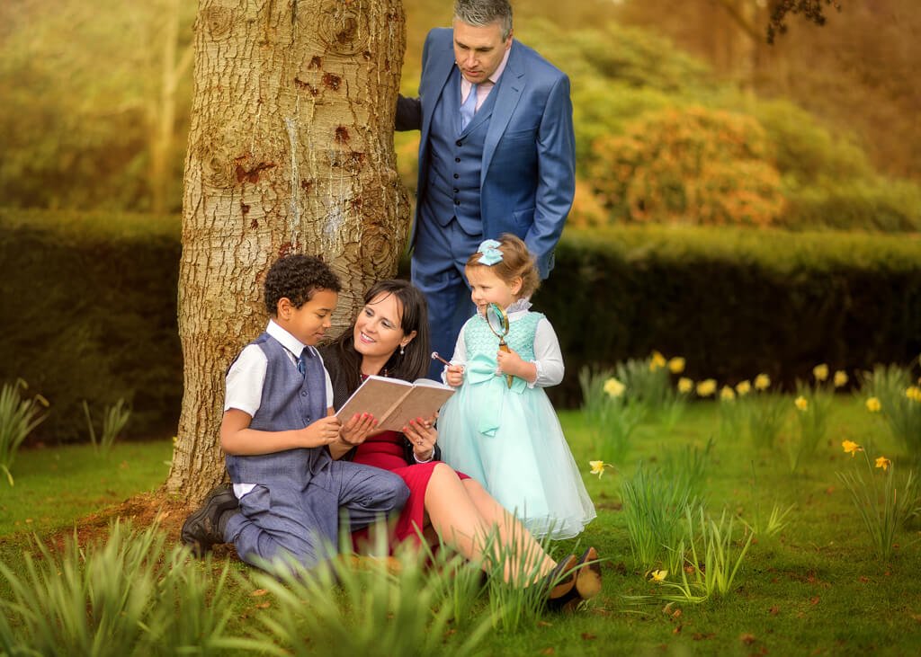 Family with Two Children Sitting under the tree among the Blooming Daffodils during Spring Photoshoot at Elvaston Castle Park by Nottingham Family Photographer.