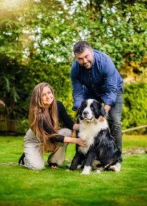Happy couple kneeling and hugging their fluffy dog during a family garden photoshoot in Nottingham