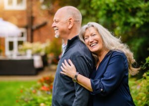Laughing couple embracing in their garden, showcasing their joyful relationship during a Nottingham photoshoot.