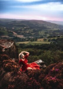 Woman in red dress overlooking a valley at sunset, professional outdoor portrait.