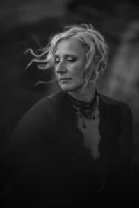 Elegant woman in contemplative pose, her hair swept by the wind, in a timeless black and white portrait.