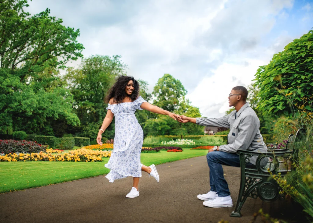 Joyful couple playing in a Nottingham garden, celebrating their engagement with laughter and love.