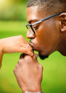 Man tenderly kissing fiancée's hand, showcasing engagement ring, symbolizing their promise in Nottingham.