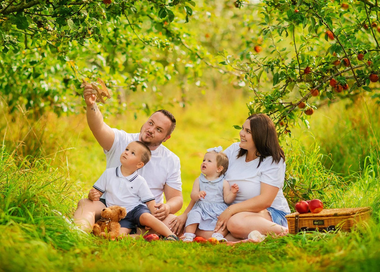 Family enjoying a picnic under apple trees, captured by a leading family photographer in Eastwood, Nottingham.
