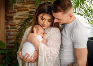 Loving parents share a close embrace with their newborn baby, a moment of pure family love captured in a lifestyle newborn photography session.