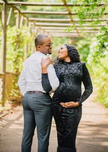 Expectant couple sharing a joyful moment under a pergola during a spring maternity photoshoot in Nottingham.