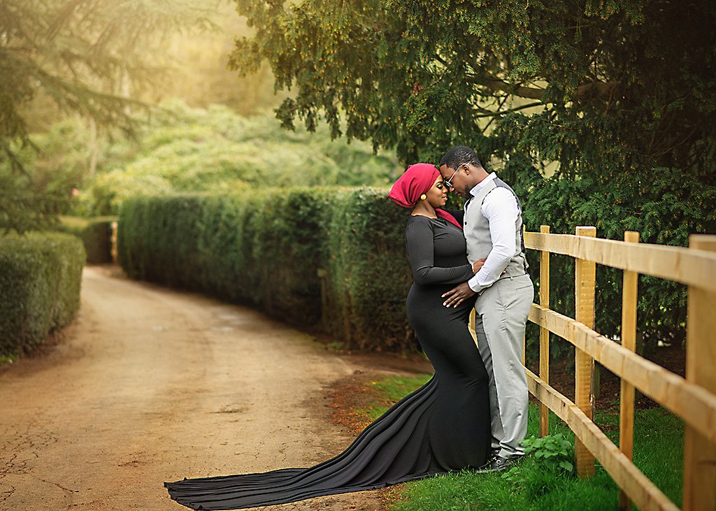An expectant couple shares an intimate moment in a lush Nottingham garden, with the mother-to-be in a stunning black gown.