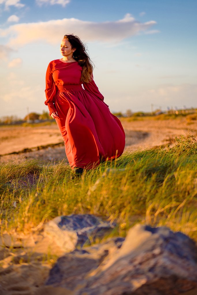 Elegant lady in a flowing red gown caught in the golden hour of an outdoor birthday photoshoot.