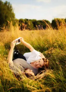 Expectant couple in Nottingham meadow holding ultrasound photos, captured by a maternity photographer.
