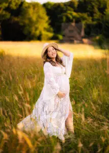Pregnant woman in white lace dress and hat during a Nottingham maternity photo shoot.