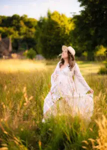Serene pregnant woman in white lace dress standing in a Nottingham field.