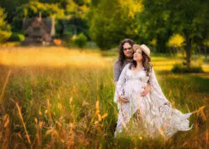 Expectant couple standing and smiling in a Nottingham field, captured during their maternity photography session.