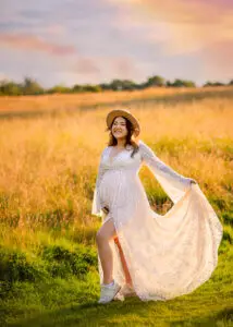 Maternity photographer Nottingham captures a joyful expectant mother in a lace dress at sunset.