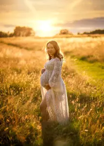 Expectant mother poses in a Nottingham field at sunset, showcasing her pregnancy glow.
