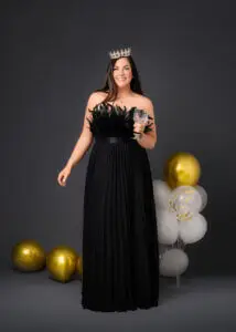 Woman in black dress with crown and champagne glass, celebrating her 40th birthday photoshoot.