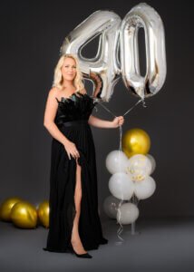 Blonde woman in black dress with '40' balloons during her 40th birthday photoshoot, celebrating a milestone birthday.