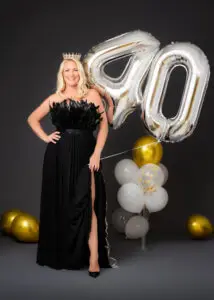 Blonde woman wearing a crown and holding '40' balloons during her 40th birthday photoshoot.
