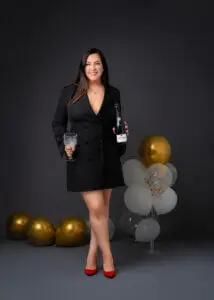 Woman in black blazer dress holding a bottle of champagne and crystal glass during her 40th birthday photoshoot.