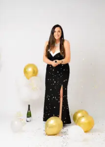 Woman in a black and white dress enjoying her 40th birthday photoshoot with confetti and gold balloons.