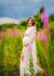 Pregnant mother wearing a lace gown in a wildflower field during a maternity photo shoot in Nottingham