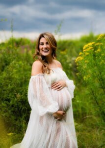 Pregnant mother smiling in a meadow with yellow wildflowers during a maternity photo shoot in Nottingham