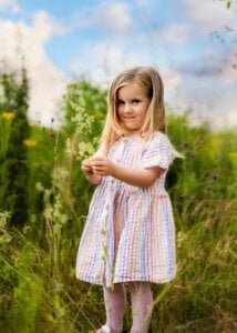 Little girl holding wildflowers in a meadow during a family photo shoot in Nottingham