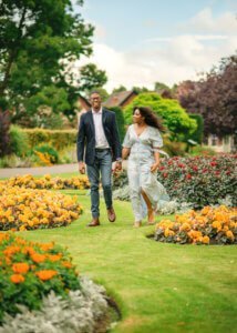 Couple walking hand in hand through a flower garden during an outdoor couple photography session in Nottingham.
