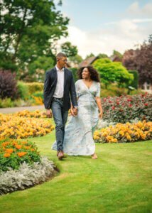 Couple holding hands and walking through a flower-filled garden during their couple photography session in Nottingham.