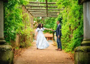 Couple holding hands under a pergola during their outdoor couple photography session in Nottingham.
