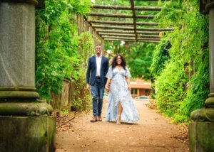 Engaged couple walking together under a pergola during their outdoor couple photography session in Nottingham.