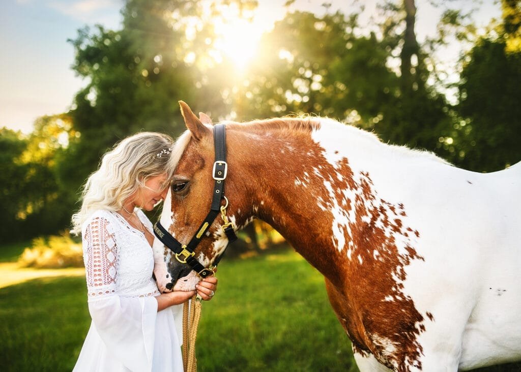 Woman gently touching her horse during a sunset equine photoshoot