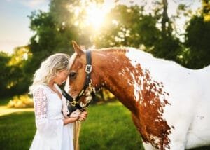 Woman gently touching her horse during a sunset equine photoshoot