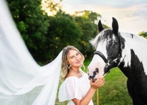 Woman in a bridal dress bonding with her horse during an equine photoshoot