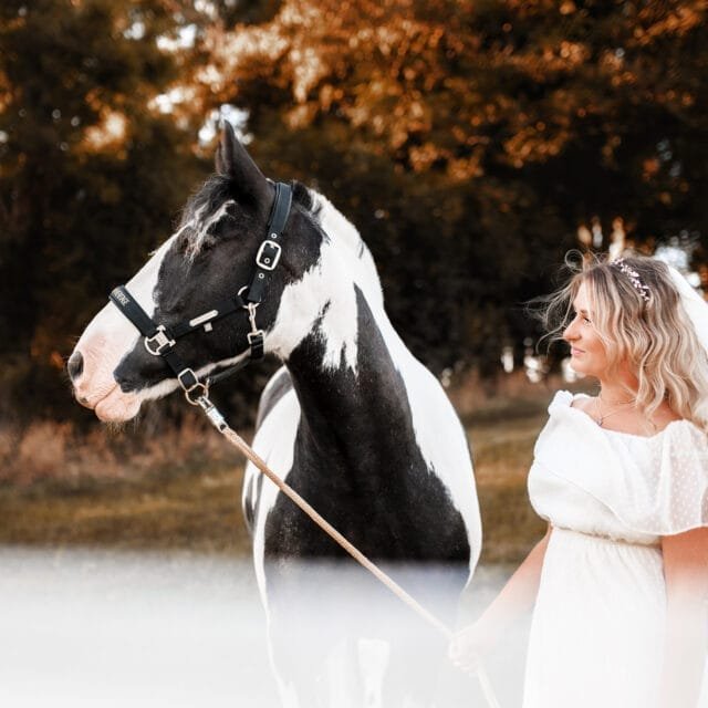 Woman standing beside her horse in an autumn-themed equine photoshoot