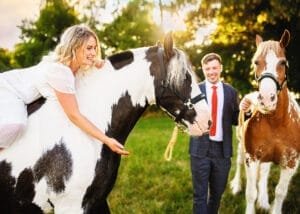 Woman riding her horse with her partner holding another horse during a photoshoot