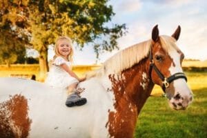 Little girl sitting on a horse during an equine photoshoot in a rural setting