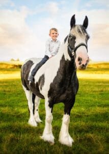 Young boy sitting on a black-and-white horse during an equine photoshoot