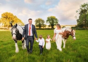 Parents walking with children and horses in the countryside during an equine photoshoot