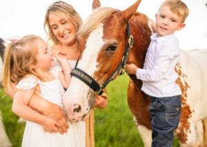 Mother with children standing beside a horse in an equine photoshoot