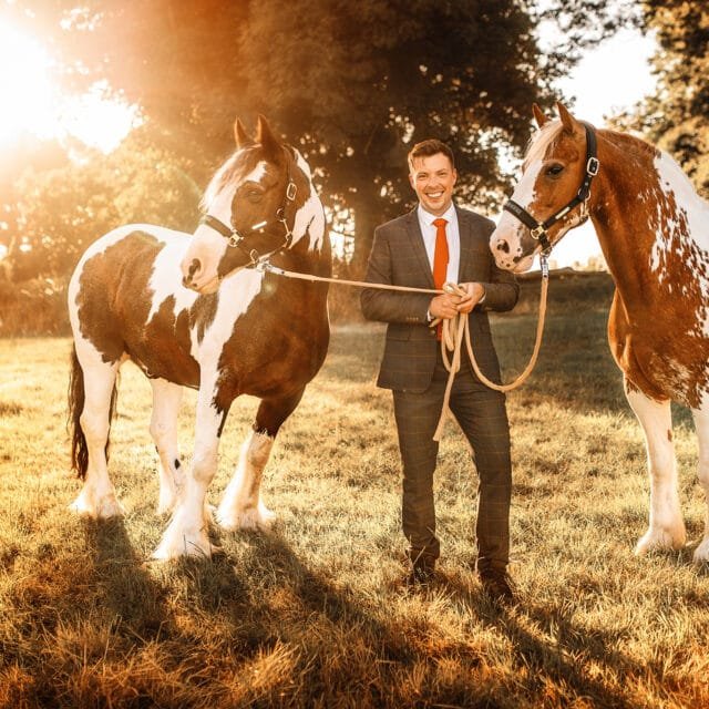 Man in a suit standing with two horses during a sunset equine photoshoot