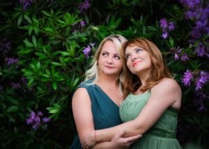 Two women embracing in front of purple flowers during a friends photoshoot in Nottingham