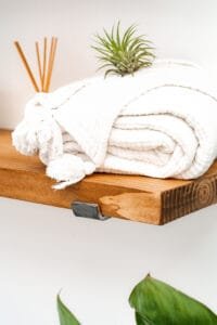 Cozy folded white blanket with air plant on wooden shelf, captured in Nottingham product photography studio.