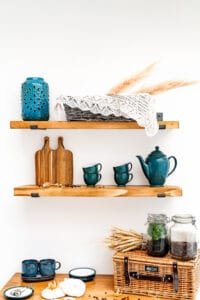 Styled wooden shelves with a wicker basket, blue ceramics, and dried wheat, photographed in Nottingham.