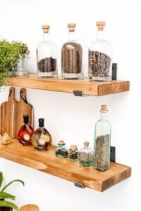 Close-up of spice jars and decor on rustic wooden shelves, captured in natural lighting for high-quality product photography.