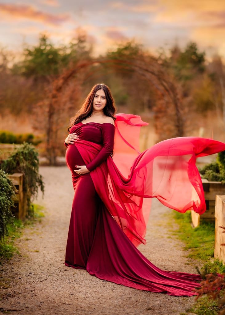 Outdoor maternity session with woman in burgundy maternity photoshoot dress at sunset